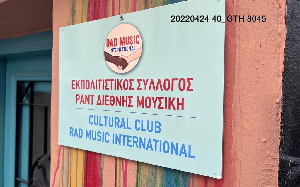 A pinkish wall with different colored vertikal strips. On top of the stripes is a signe with the inscription 